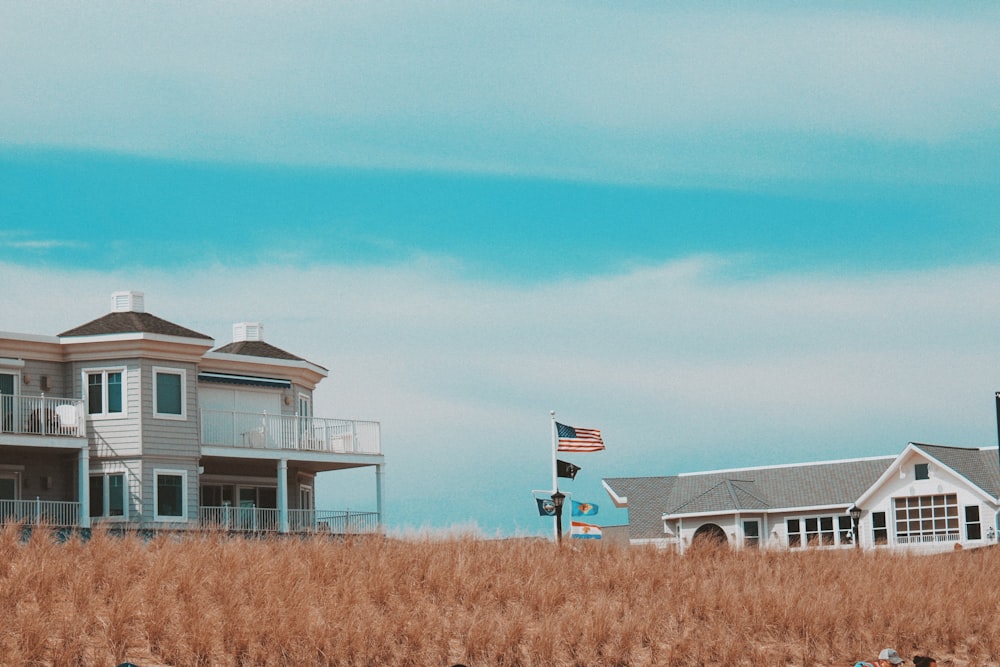 Weißes und graues Haus auf braunem Rasenfeld unter blauem Himmel tagsüber