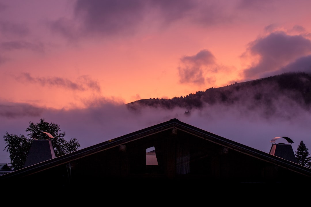 silhouette of house under cloudy sky during sunset