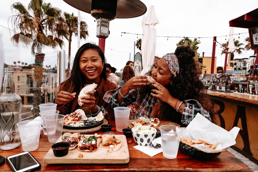 2 women sitting on chair in front of table with foods