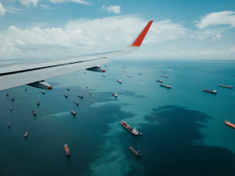white and red airplane wing over the sea during daytime