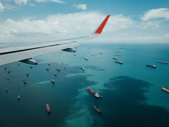white and red airplane wing over the sea during daytime
