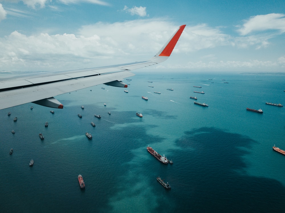 white and red airplane wing over the sea during daytime