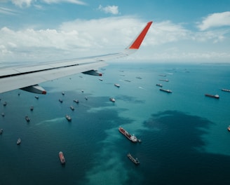 white and red airplane wing over the sea during daytime