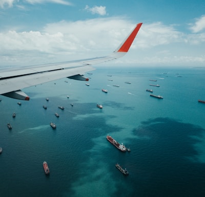 white and red airplane wing over the sea during daytime