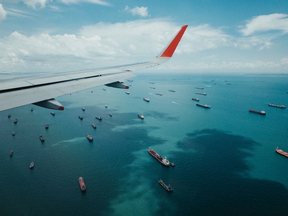 Ala bianca e rossa dell'aeroplano sopra il mare durante il giorno
