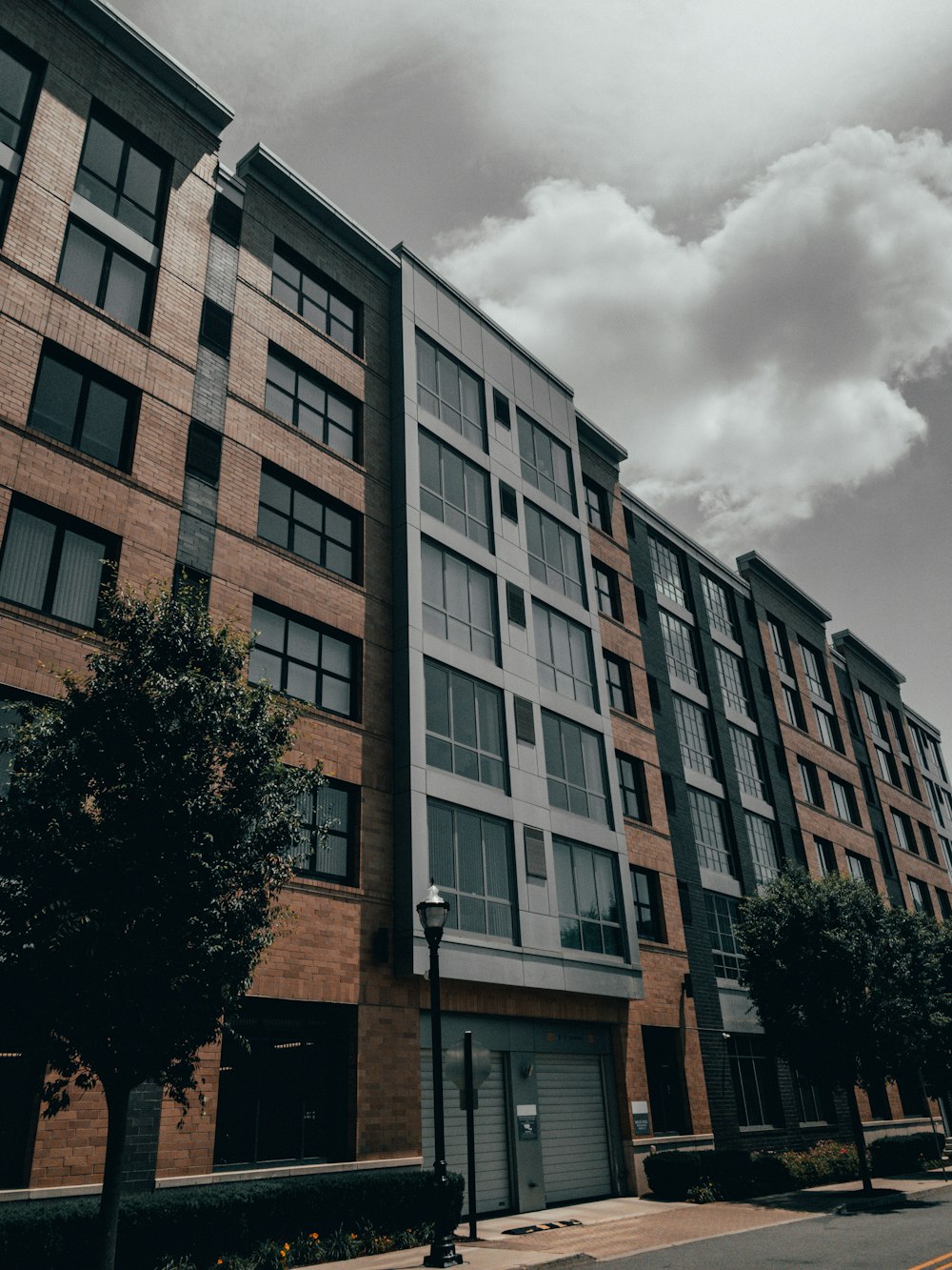 brown concrete building near green trees under white clouds during daytime