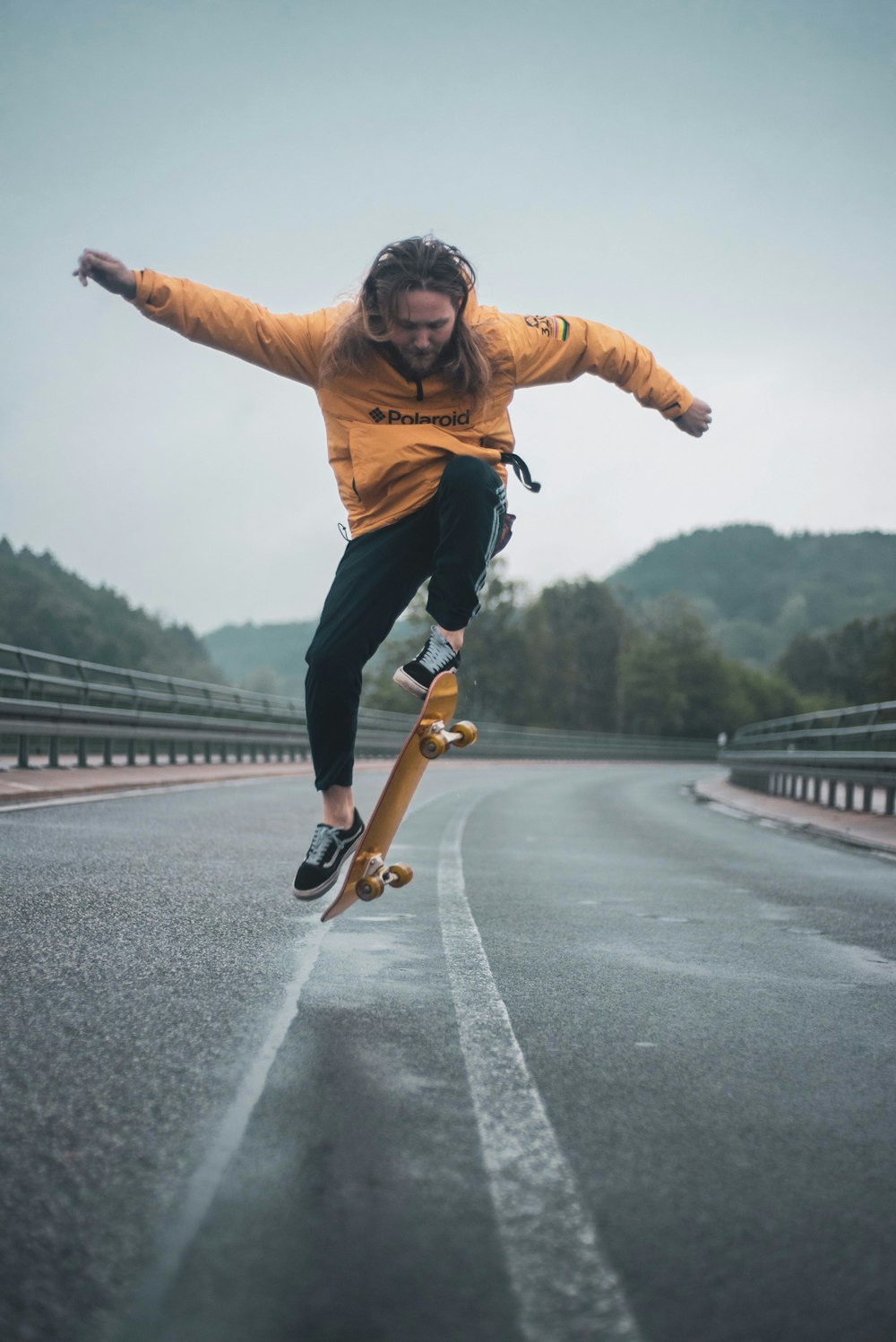 man in brown jacket and black pants riding skateboard on gray concrete road during daytime