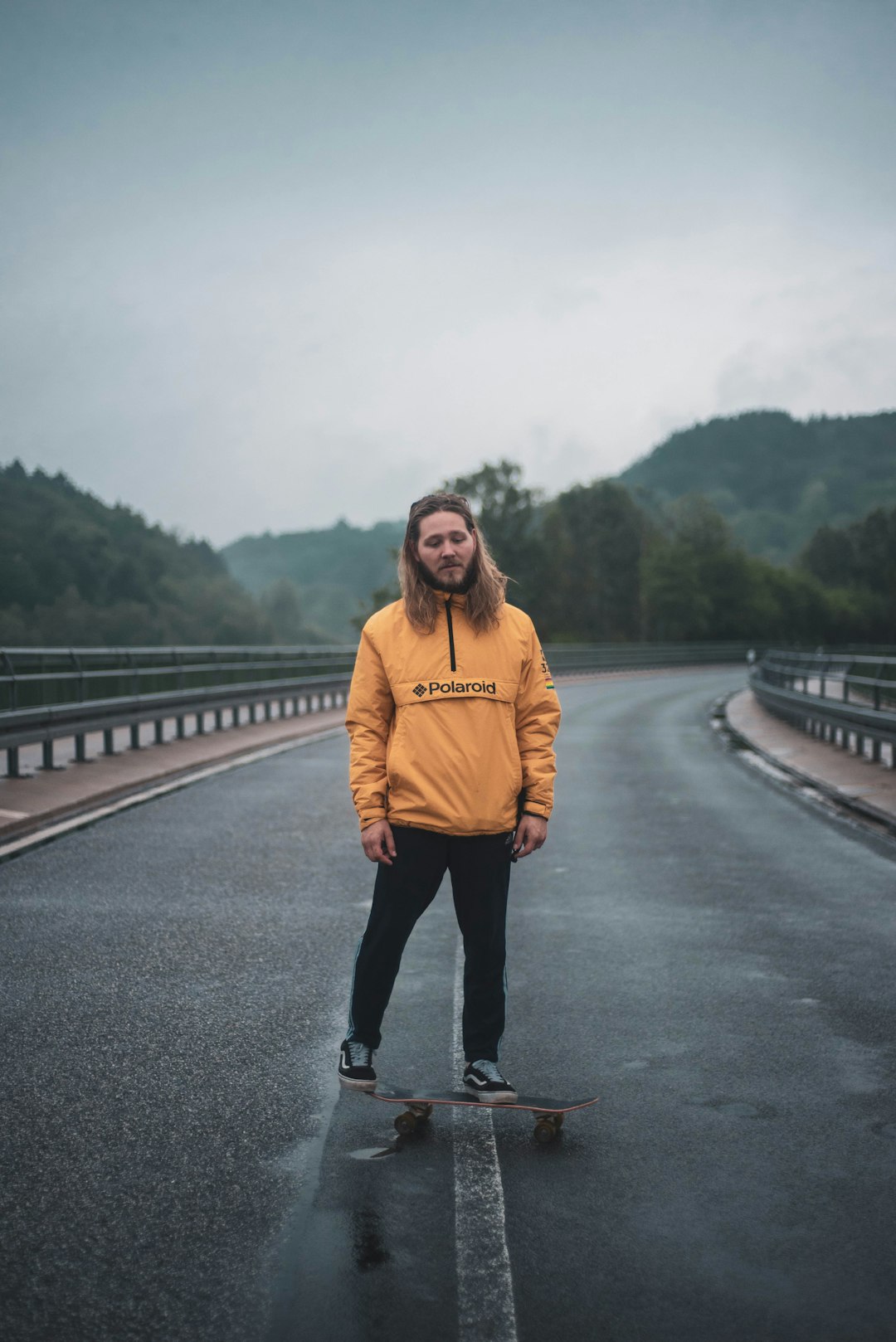 woman in yellow hoodie standing on gray concrete bridge during daytime