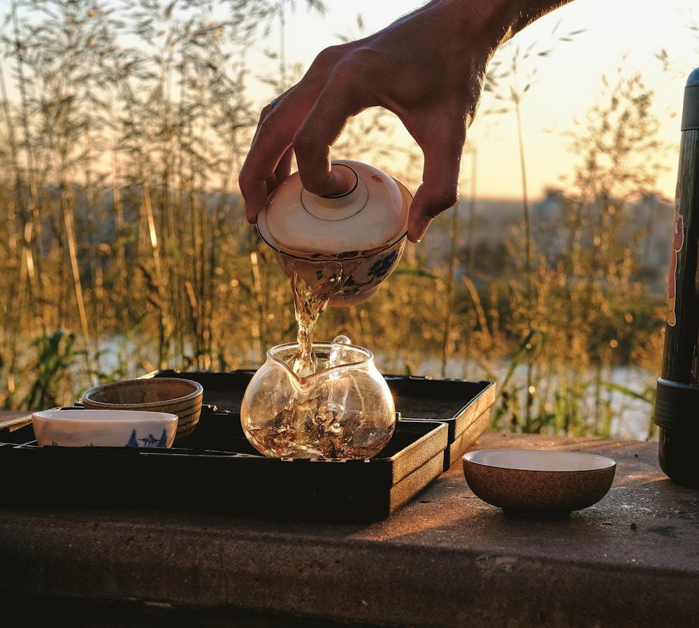 person pouring water on clear glass jar