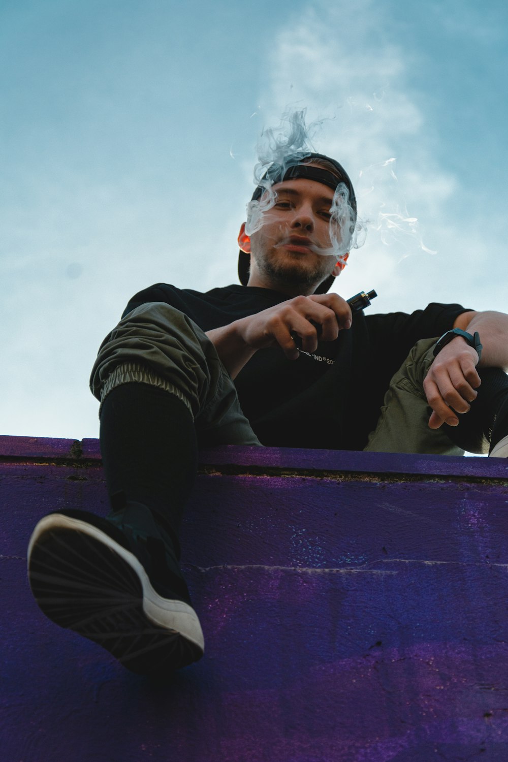 man in black jacket and blue denim jeans sitting on bench during daytime