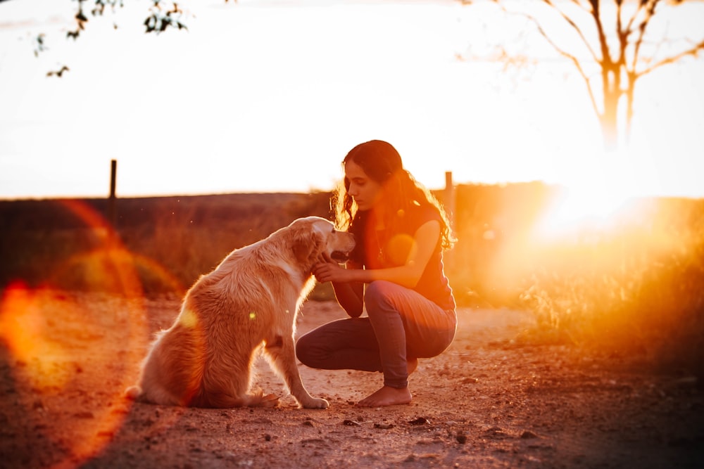 woman in orange shirt and black pants sitting on brown dirt during sunset