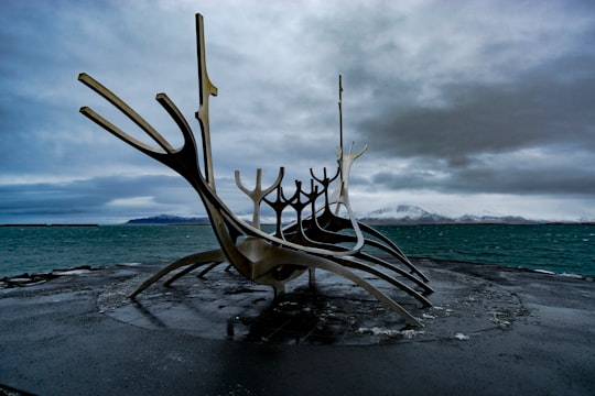 white wooden chair on beach during daytime in Viking Boat Sculpture Iceland
