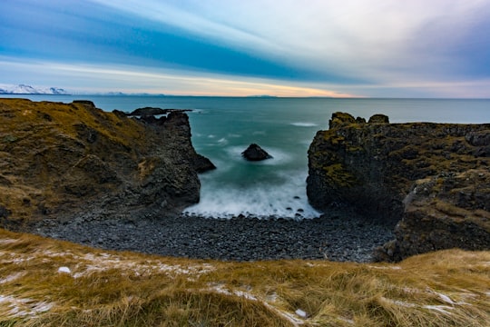 brown rock formation on sea under blue sky during daytime in Gatklettur Iceland
