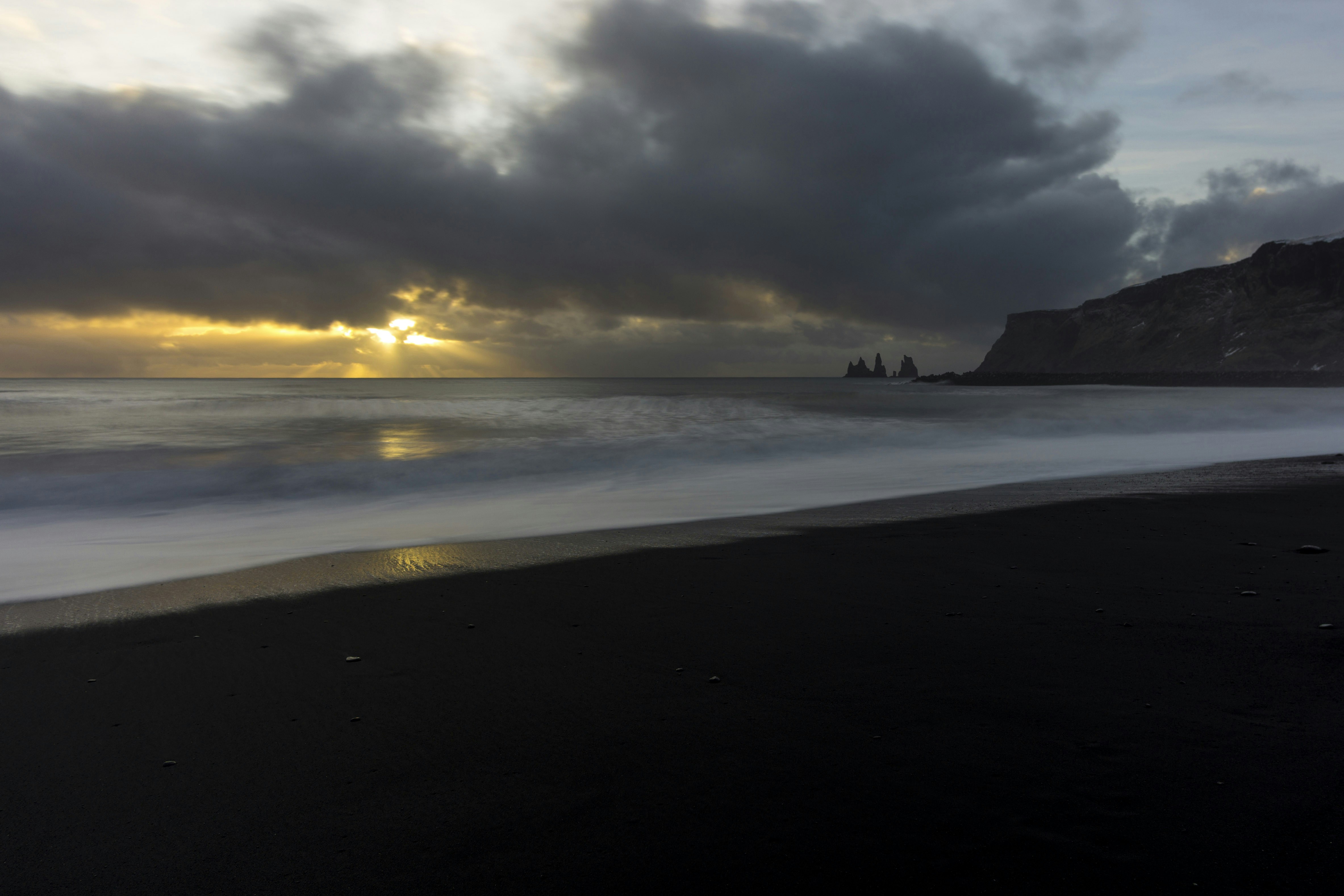 silhouette of person standing on seashore during sunset