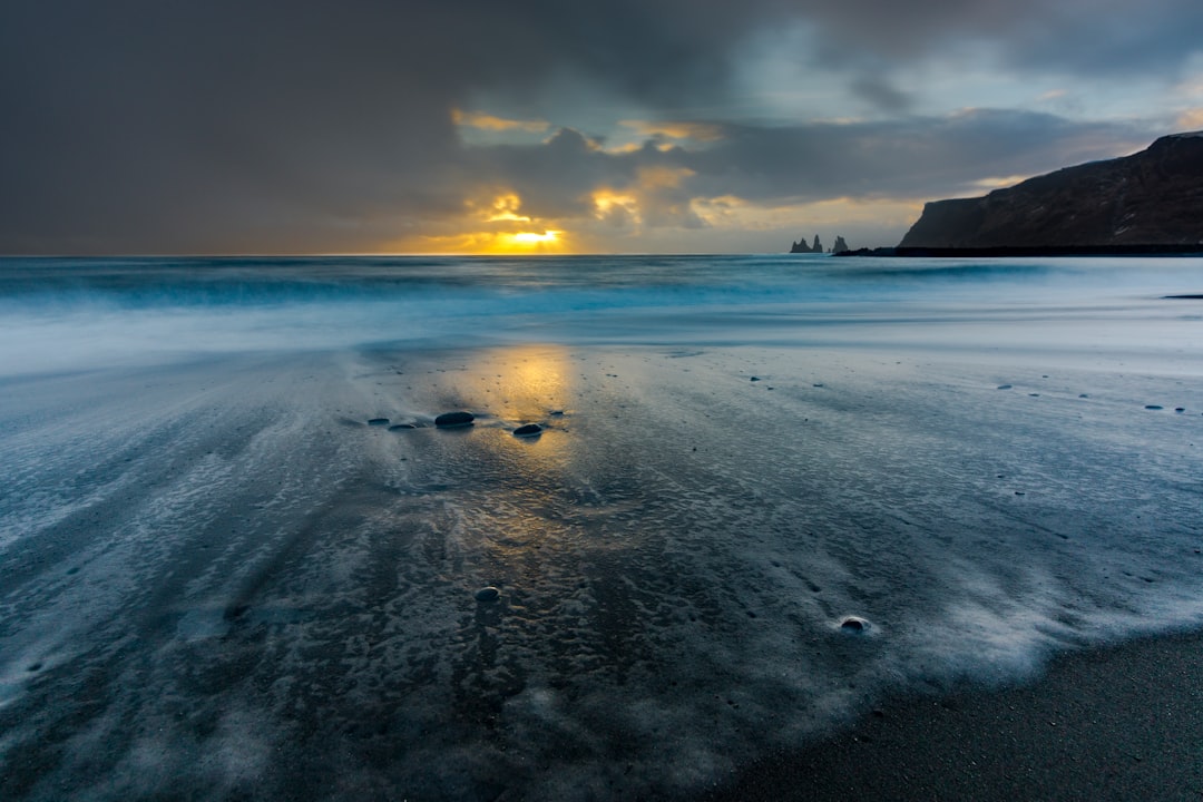 body of water under cloudy sky during sunset