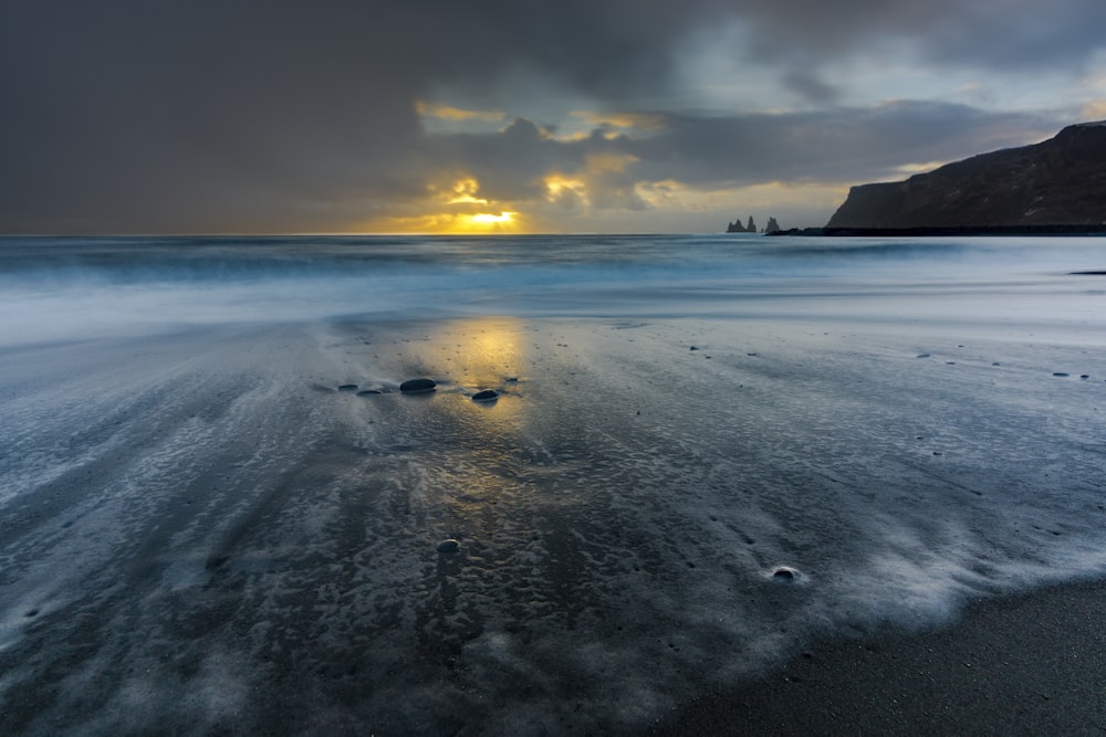 body of water under cloudy sky during sunset