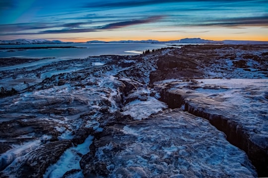 rocky shore under blue sky during daytime in Snæfellsnes Iceland