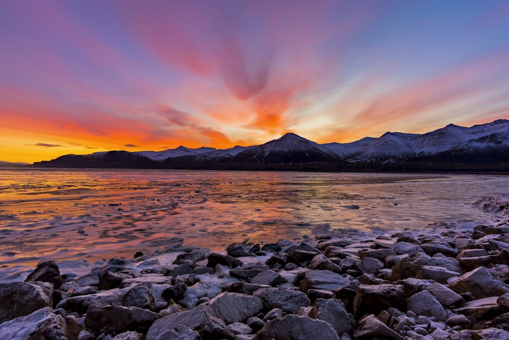 gray rocks near body of water during sunset