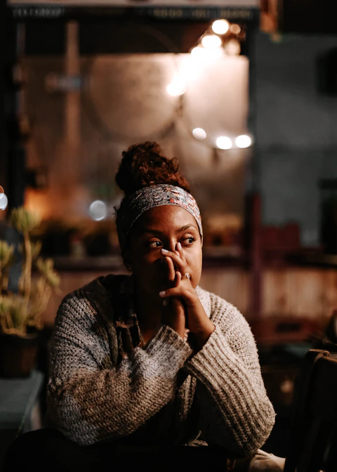 A woman with a headband and hair in a bun, hands near her face