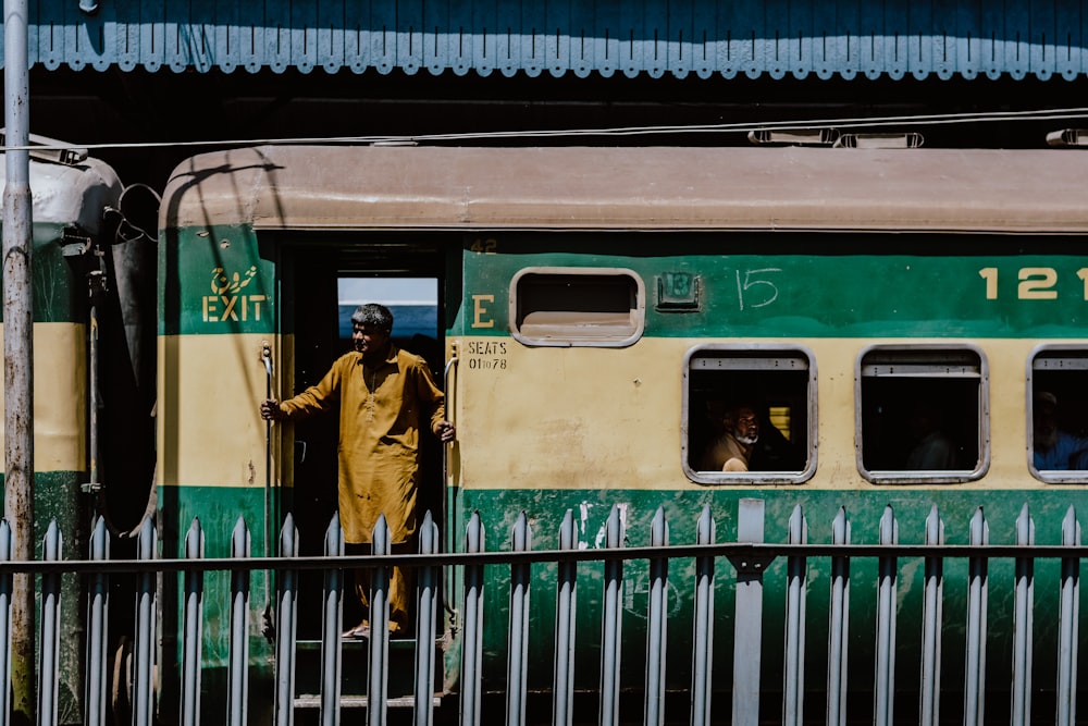 woman in brown coat standing beside green train