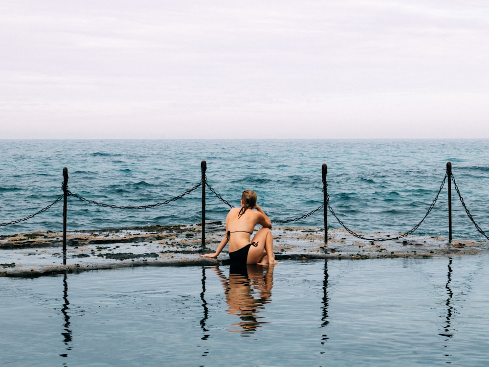 woman in black bikini standing on water during daytime