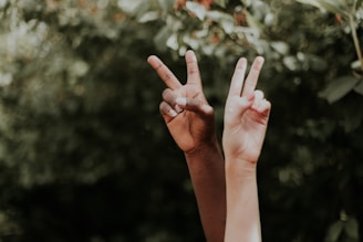 Peace sign gesture by two hands in front of a green background, reflecting grassroots movements 