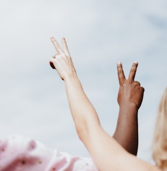 woman in white and pink floral shirt raising her hands