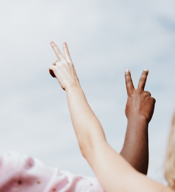 woman in white and pink floral shirt raising her hands