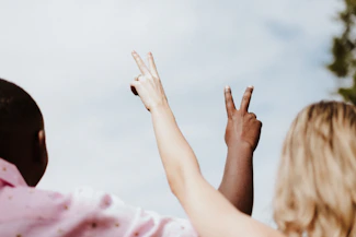 woman in white and pink floral shirt raising her hands