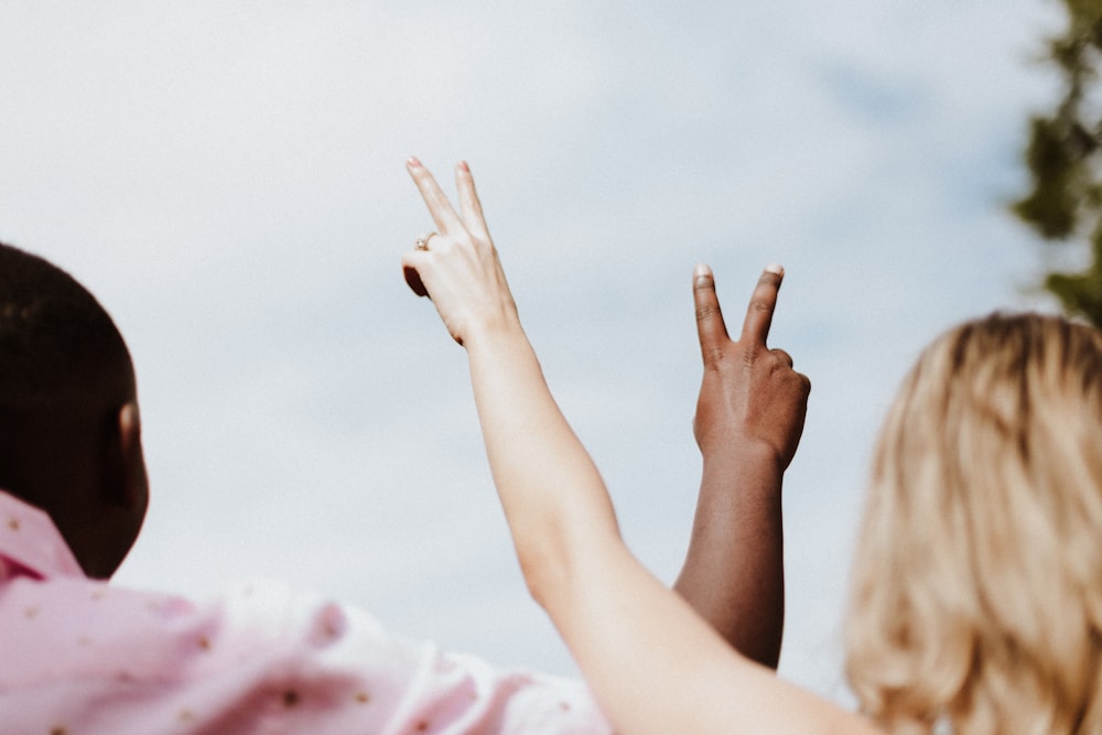 woman in white and pink floral shirt raising her hands