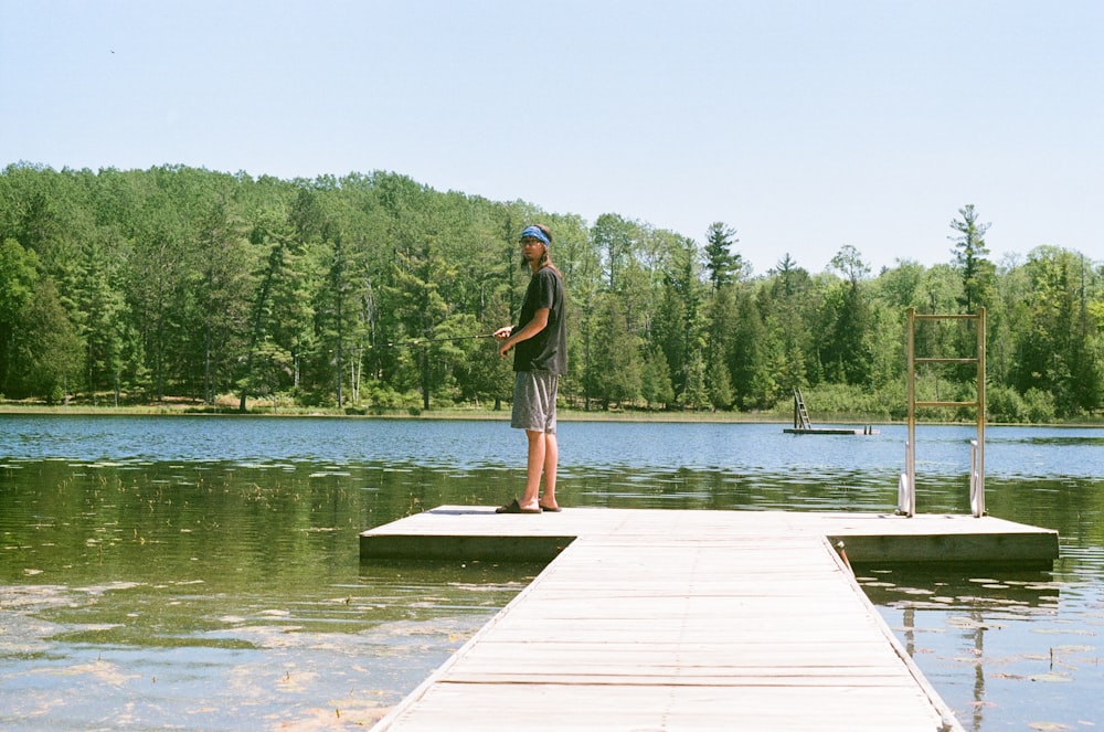 woman in black shirt standing on dock near lake during daytime