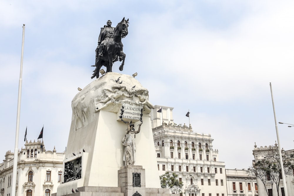 man riding horse statue near white concrete building during daytime