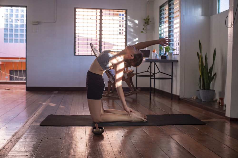 Mujer con pantalones cortos negros y camiseta blanca sin mangas haciendo yoga