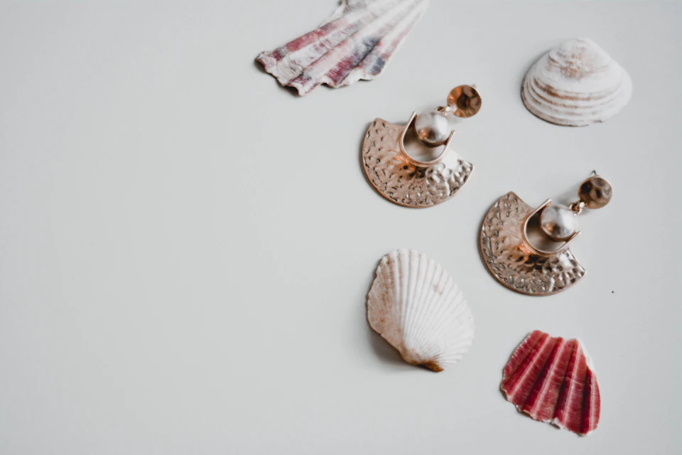 Anting mutiara di samping kerang di atas permukaan putih