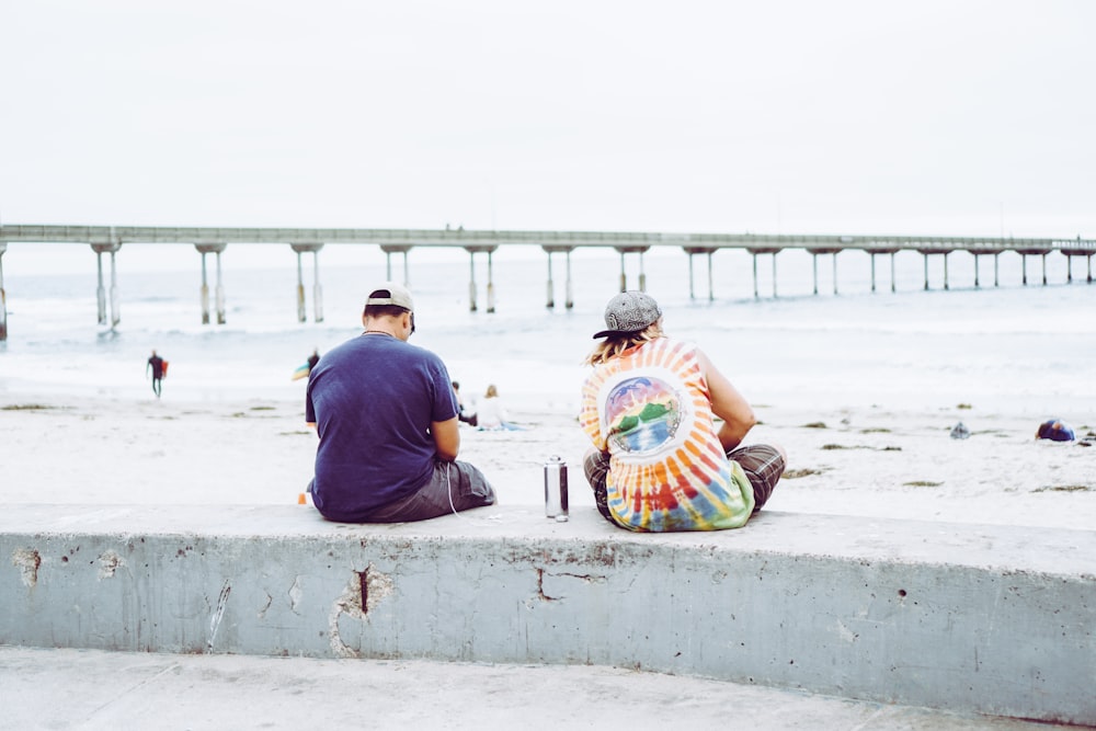 man in blue shirt sitting on concrete bench near body of water during daytime