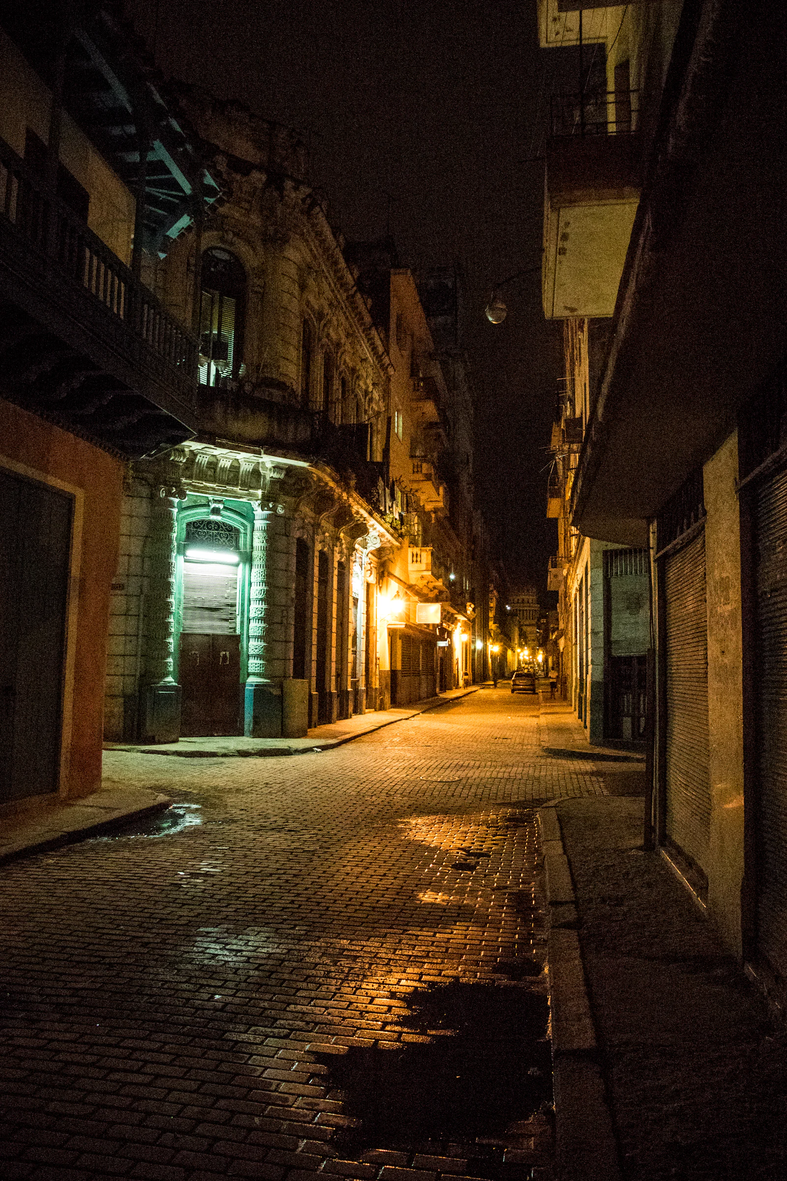 An empty colonial street in Havana at night under sodium light.