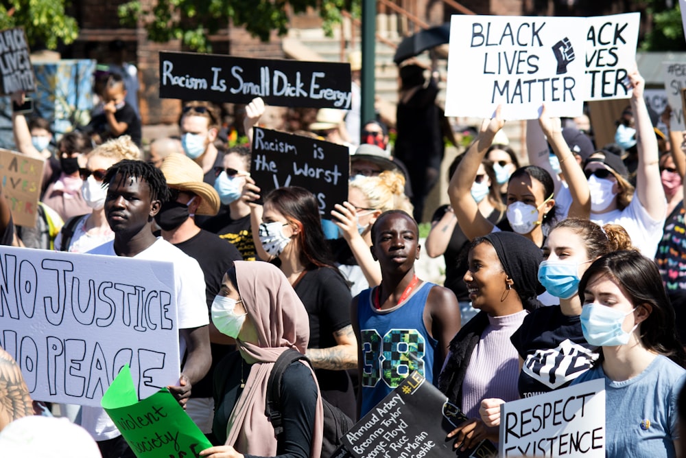 a crowd of people holding signs and wearing masks