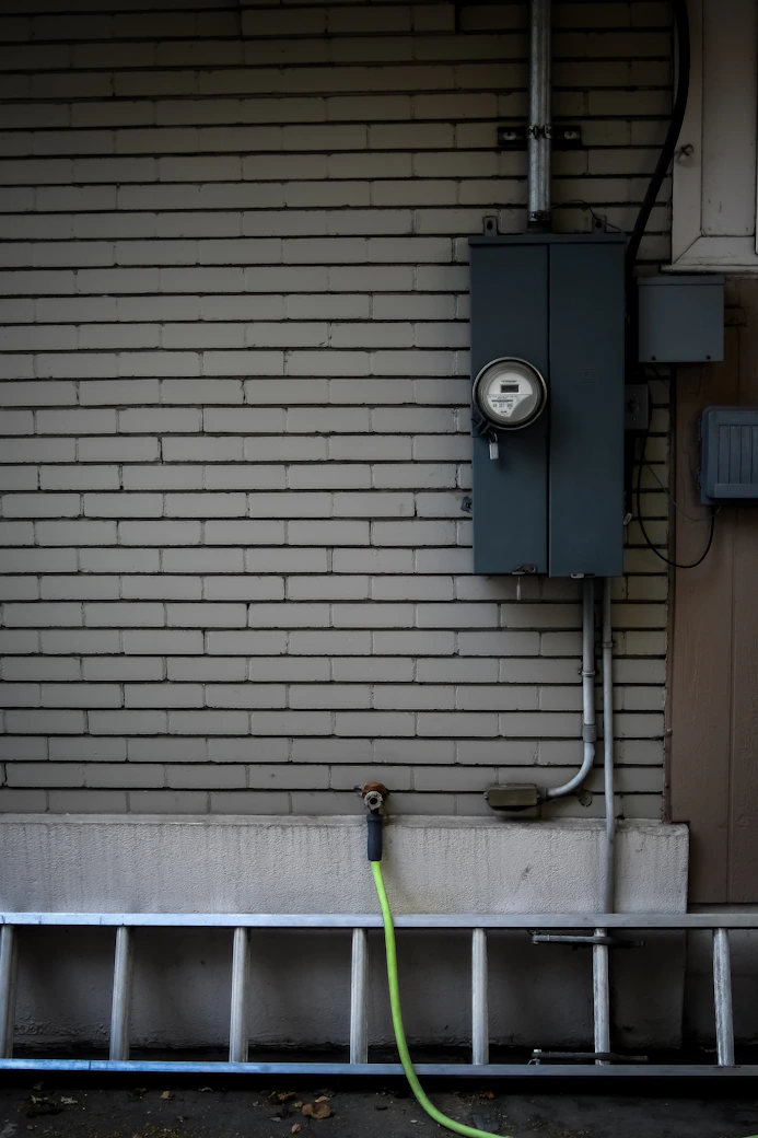 A friendly electrician speaking with a homeowner beside a newly installed meter base in Coeur d'Alene.