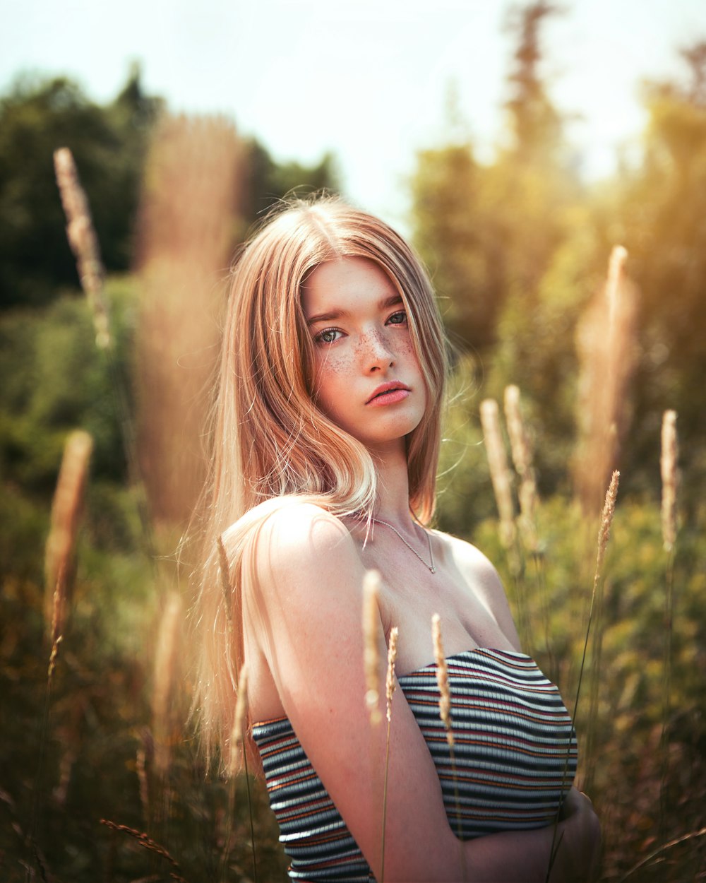 woman in black and white stripe tank top standing near brown grass during daytime