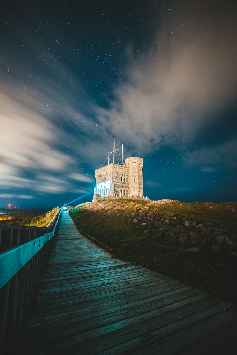 white concrete building on brown wooden bridge under blue sky during night time