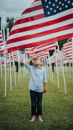 boy in blue dress shirt standing on green grass field during daytime