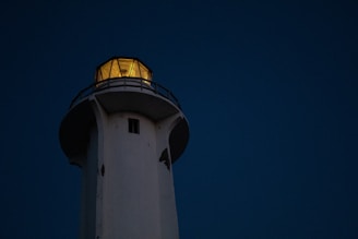 A warm lighthouse shining its light over calm seas at dusk, symbolizing guidance and illumination.