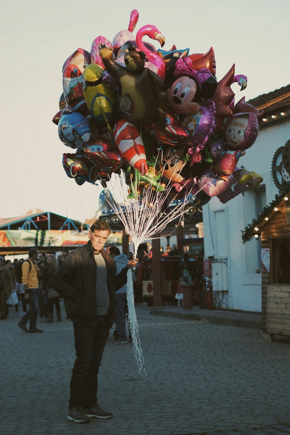 man in black jacket holding balloons