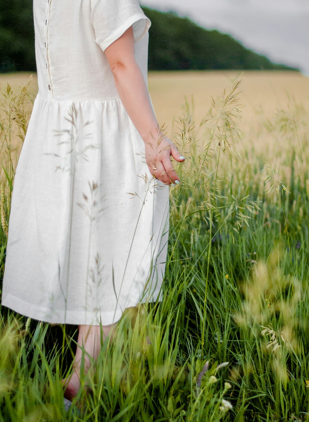 Mujer en vestido blanco de pie en el campo de hierba verde durante el día