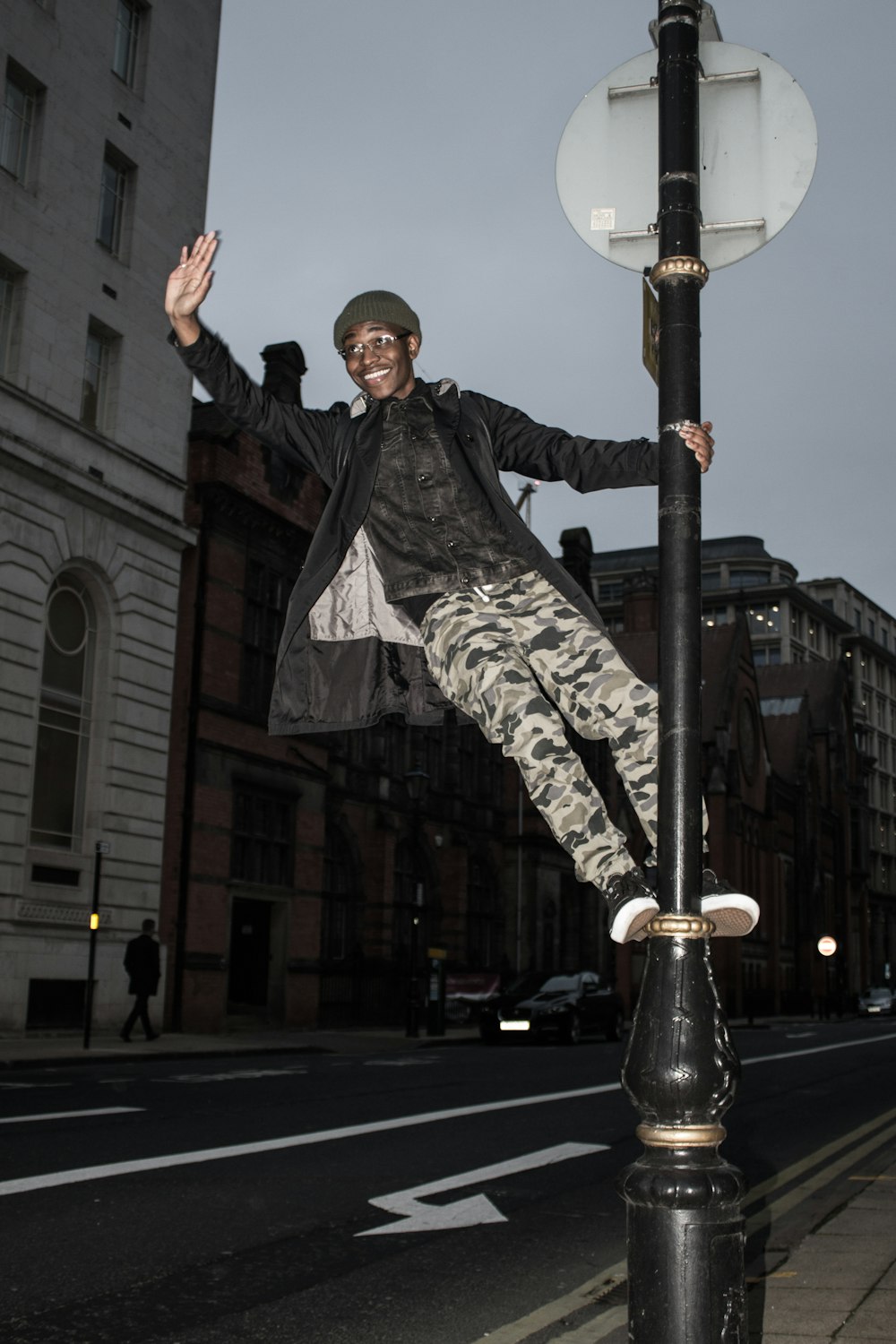 man in black jacket and gray pants standing on gray metal post during daytime