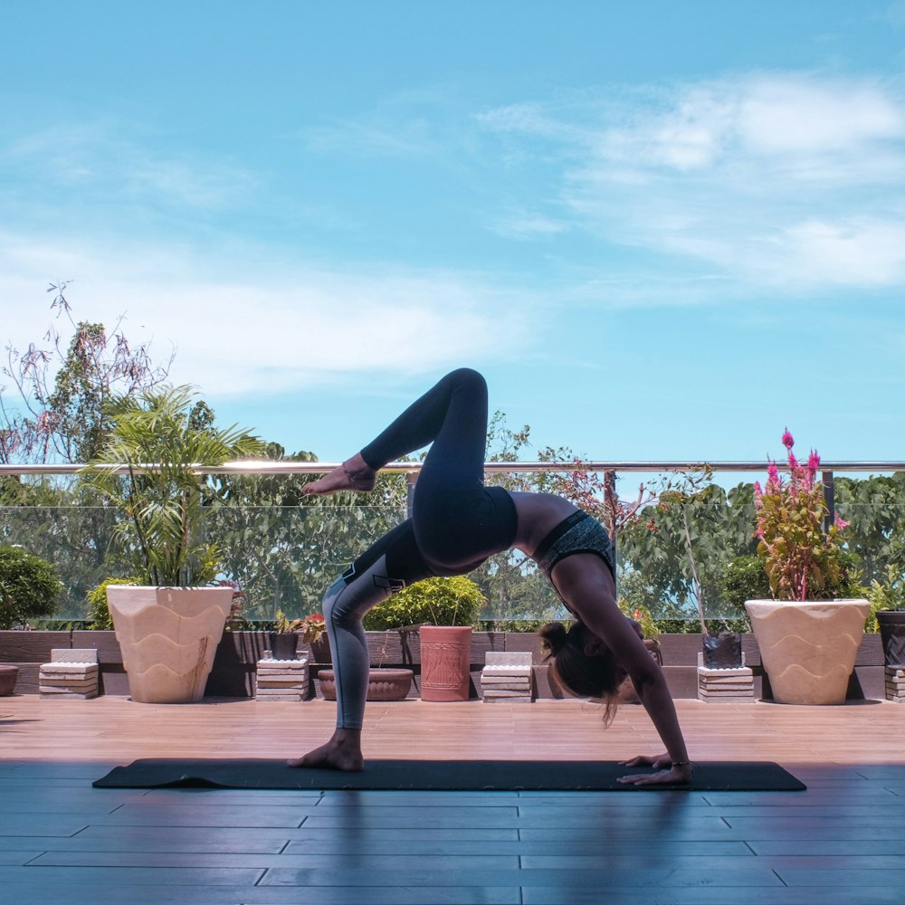 mulher em leggings pretas e regata preta fazendo yoga