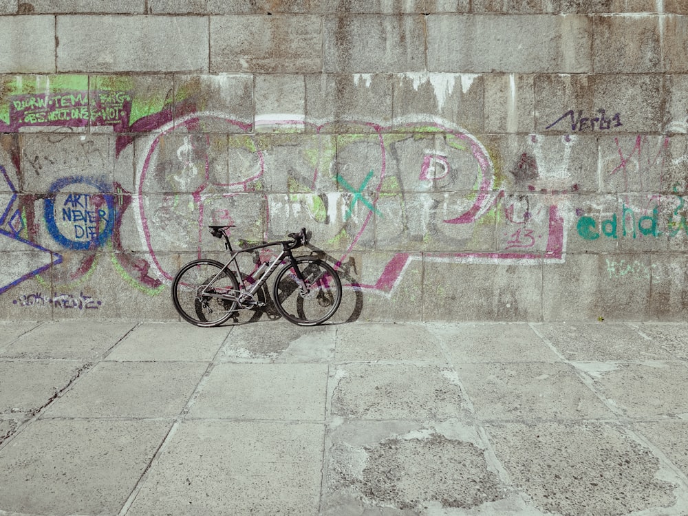 black bicycle parked beside wall with graffiti