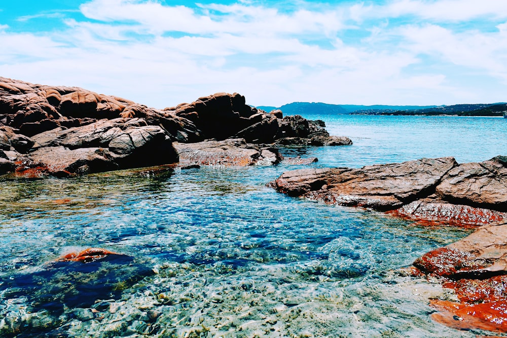 brown rock formation on blue sea under blue sky during daytime