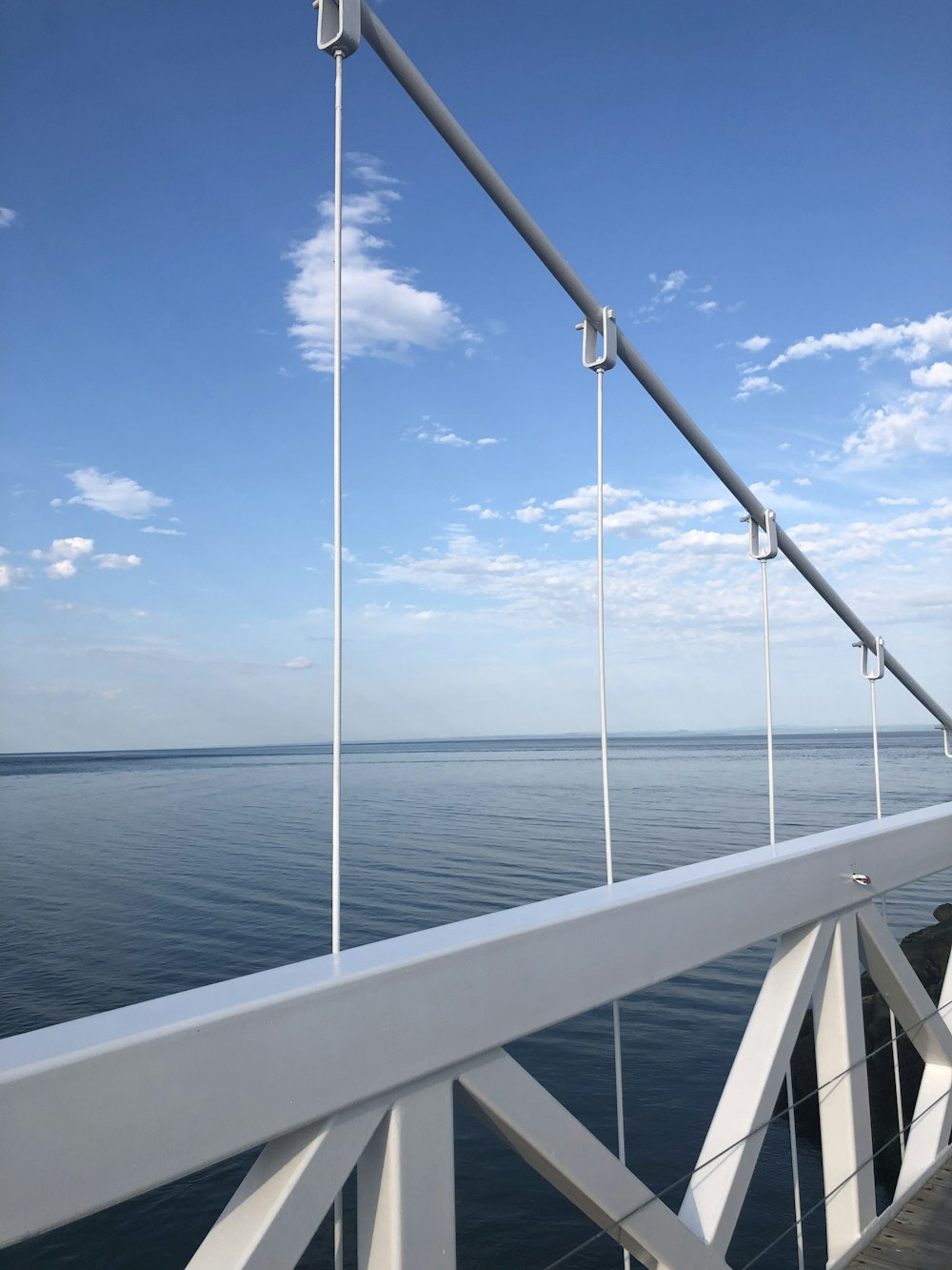 昼間の青空の下、青い海に架かるホワイトメタル橋