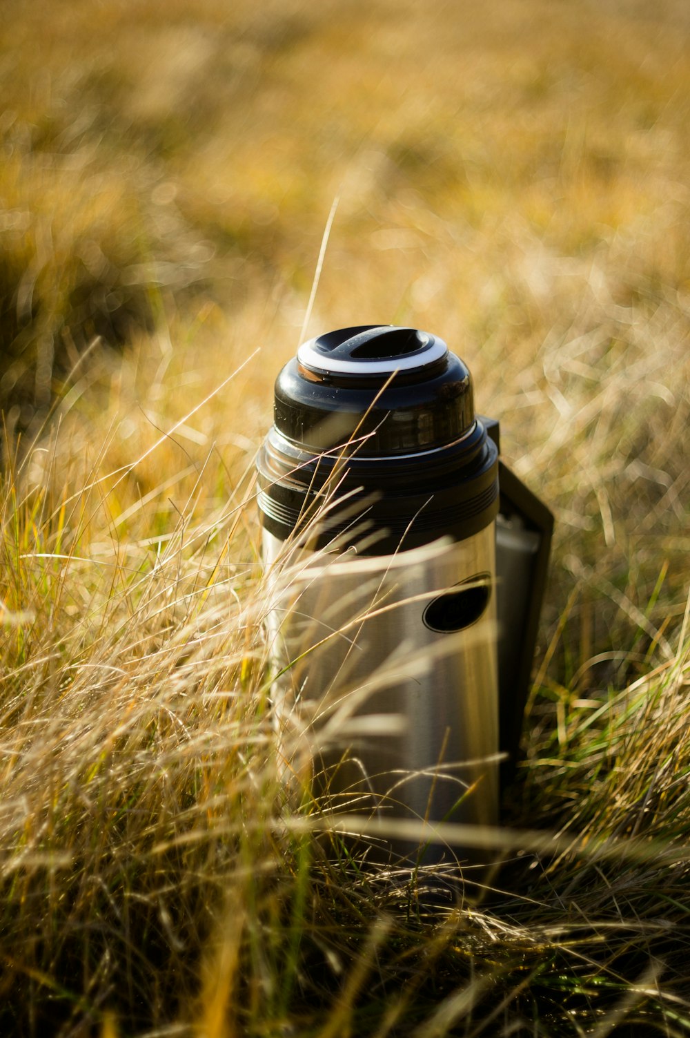 white and black vacuum flask on green grass